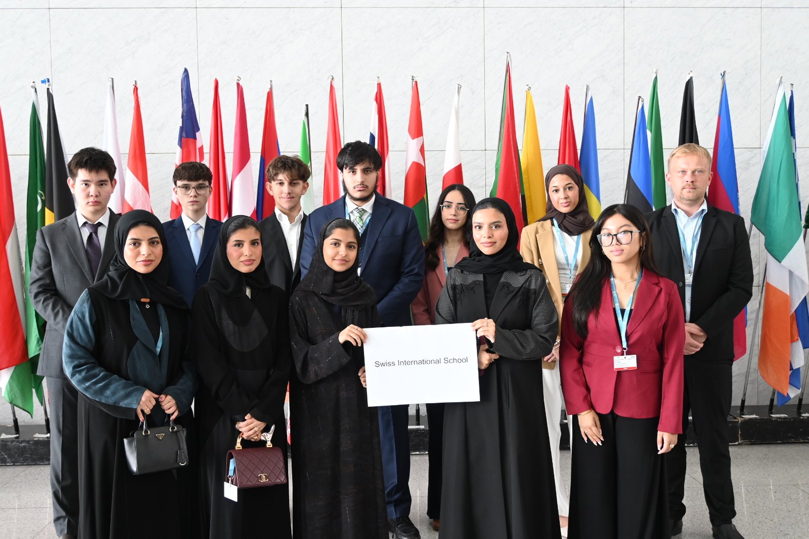 The Swiss International School delegation holding their school placard in front of the national flags at Doha MUN 2026.